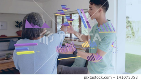 Guiding mint-polo man assisting blue-sweater senior raising arm at home, with AR charts and watch Guiding mint-polo man assisting blue-sweater senior raising arm at home, with AR charts and watch 141075358