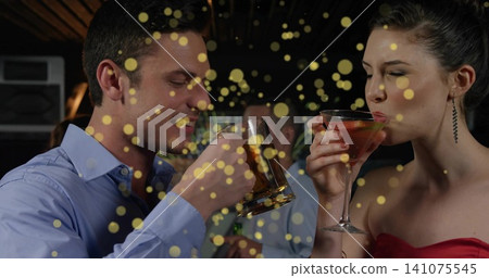 Sipping blue-shirted man and red-clad woman at bar, holding beer mug and martini Sipping blue-shirted man and red-clad woman at bar, holding beer mug and martini 141075545