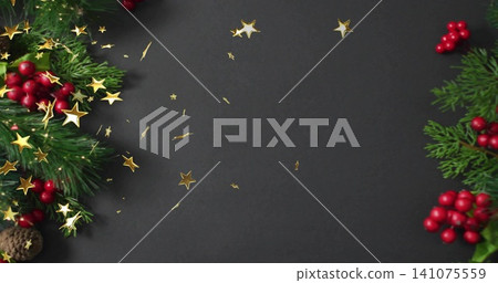 Composing flat-lay on dark charcoal surface with pine sprigs, red berries, pine cone, gold stars Composing flat-lay on dark charcoal surface with pine sprigs, red berries, pine cone, gold stars 141075559