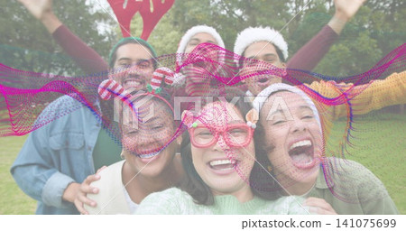 Smiling friends posing for selfie in park wearing sweaters and pink glasses with magenta overlay 141075699