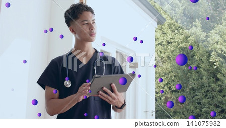 Standing male medic checking tablet on home porch, in navy scrubs, stethoscope, purple spheres Standing male medic checking tablet on home porch, in navy scrubs, stethoscope, purple spheres 141075982