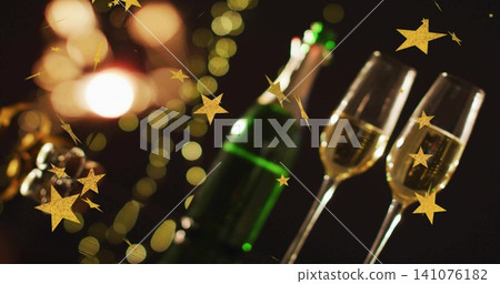Showing two clear champagne flutes bubbly on party table with green bottle, gold stars, copy space Showing two clear champagne flutes bubbly on party table with green bottle, gold stars, copy space 141076182