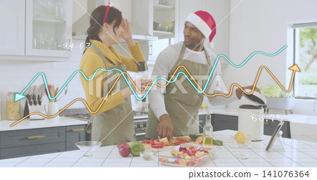 Preparing couple with reindeer headband and Santa hat chopping at kitchen island slow cooker tablet 141076364