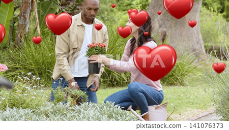 Handing couple passing potted plant in garden, woman wearing pink top, pink can, trowel, red hearts Handing couple passing potted plant in garden, woman wearing pink top, pink can, trowel, red hearts 141076373