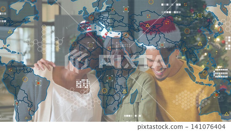 Smiling trio leaning on couch at home, wearing Santa hats, casual wear, Christmas tree, map overlay Smiling trio leaning on couch at home, wearing Santa hats, casual wear, Christmas tree, map overlay 141076404