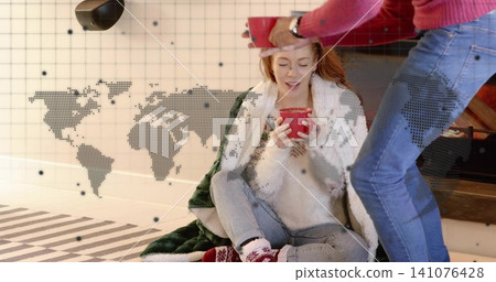 Cradling woman wrapped in blanket holding red mug near low hearth, red-sweatered man offering mug Cradling woman wrapped in blanket holding red mug near low hearth, red-sweatered man offering mug 141076428