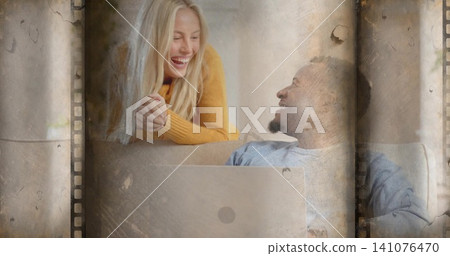 Laughing woman leaning over couch at home, man reclining with laptop, film borders, mustard sweater Laughing woman leaning over couch at home, man reclining with laptop, film borders, mustard sweater 141076470