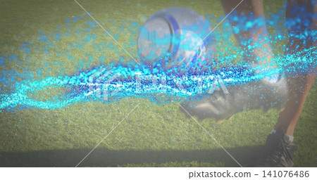 Kicking adult wearing dark shorts, black cleats sending soccer ball on grassy field with blue trail Kicking adult wearing dark shorts, black cleats sending soccer ball on grassy field with blue trail 141076486