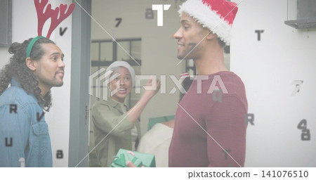 Holding green gift, man wearing Santa hat greeting host wearing headwrap at doorway, copy space Holding green gift, man wearing Santa hat greeting host wearing headwrap at doorway, copy space 141076510