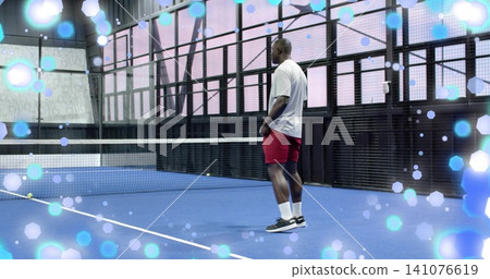 Standing athlete in white tee, red shorts on blue court with net, tennis balls, copy space Standing athlete in white tee, red shorts on blue court with net, tennis balls, copy space 141076619