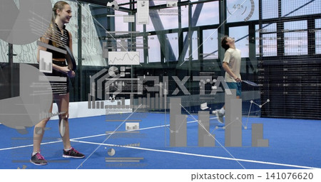 Standing female holding racket on blue glass padel court wearing striped-dress, AR data, copy space Standing female holding racket on blue glass padel court wearing striped-dress, AR data, copy space 141076620