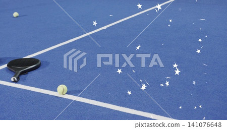 Lying black paddle near court line on blue with two tennis balls and confetti, copy space Lying black paddle near court line on blue with two tennis balls and confetti, copy space 141076648