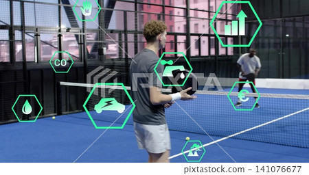 Holding paddle, male wearing gray shirt and band preparing serve on blue court, with green icons 141076677