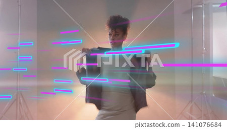Standing woman wearing sleeveless top and skirt, holding dark jacket in studio with neon streaks Standing woman wearing sleeveless top and skirt, holding dark jacket in studio with neon streaks 141076684