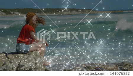 Sitting woman in red top, denim shorts on rocky outcrop by surf, sparkle overlay, copy space Sitting woman in red top, denim shorts on rocky outcrop by surf, sparkle overlay, copy space 141076822