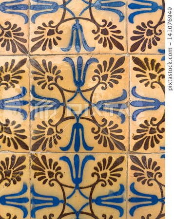 Vintage Portuguese azulejo tiles featuring an ornate symmetrical floral pattern in shades of blue and deep brown set against a rustic yellow background Vintage Portuguese azulejo tiles featuring an ornate symmetrical floral pattern in shades of blue and deep brown set against a rustic yellow background 141076949