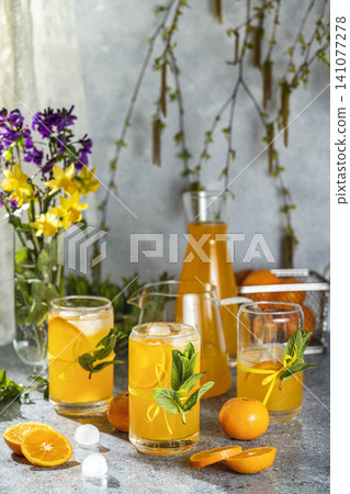 Refreshing cold citrus lemonade decorated with mint being poured into glasses Refreshing cold citrus lemonade decorated with mint being poured into glasses 141077278