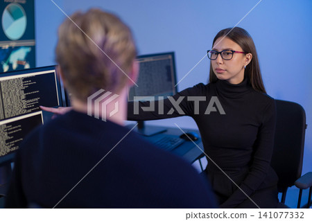 IT professionals collaborating in a secure operations center with code displayed on screens 141077332
