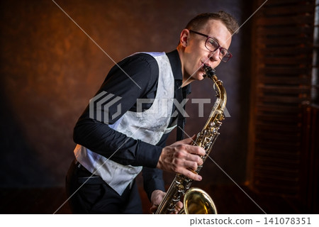 An elegant man in glasses playing golden saxophone 141078351