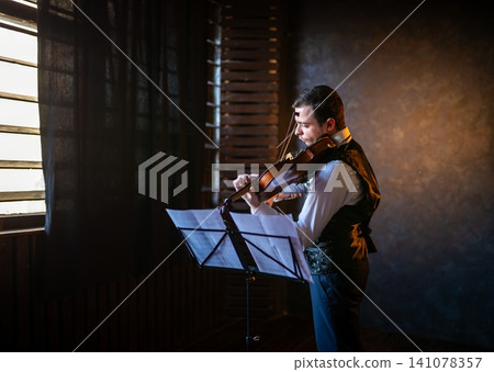 Violinist in profile playing behind sheet music Violinist in profile playing behind sheet music 141078357