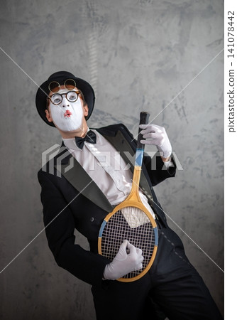 Funny male mime holding a tennis racket like a guitar Funny male mime holding a tennis racket like a guitar 141078442