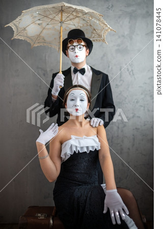 Mime couple posing together with a lace umbrella and a suitcase Mime couple posing together with a lace umbrella and a suitcase 141078445