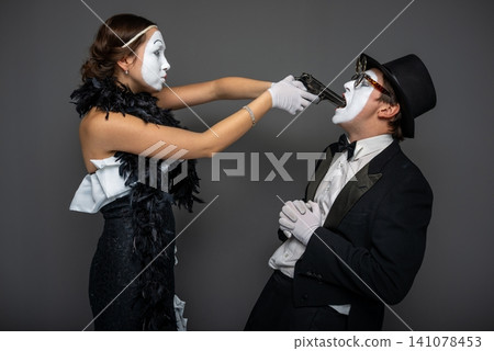 Dramatic mime scene with a female pointing a toy gun at her partner Dramatic mime scene with a female pointing a toy gun at her partner 141078453