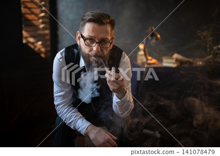 Elegant gentleman smoking a traditional pipe at his desk Elegant gentleman smoking a traditional pipe at his desk 141078479