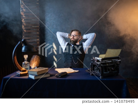 Relaxed writer resting at his desk with hands behind head Relaxed writer resting at his desk with hands behind head 141078495