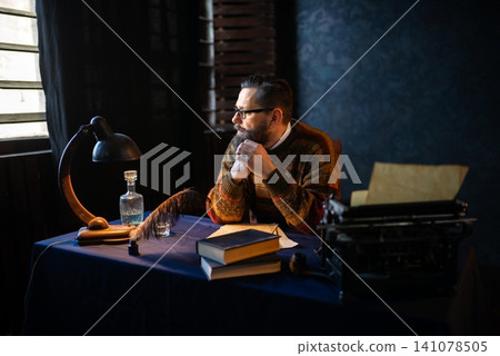 Thoughtful man writer sitting at a vintage writing desk 141078505