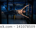 Strong athlete performing a human flag exercise on metal wall rungs 141078509