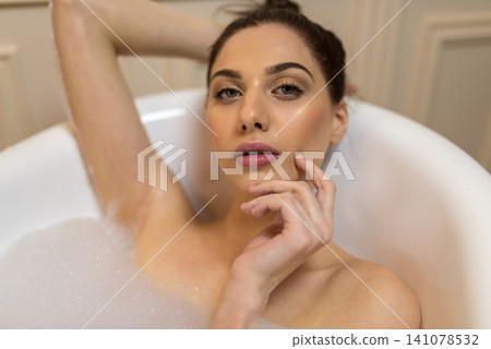 Sensual woman looking directly forward while leaning back in a soap bath Sensual woman looking directly forward while leaning back in a soap bath 141078532