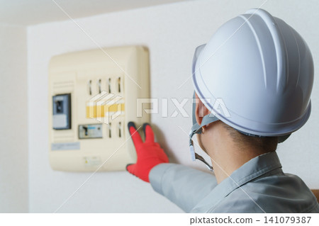 Workers inspecting distribution boards and circuit breakers Workers inspecting distribution boards and circuit breakers 141079387