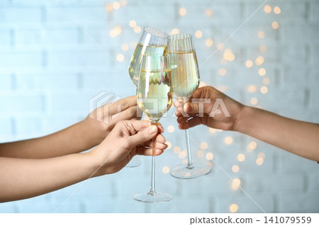 People clinking glasses of champagne against blurred lights, closeup People clinking glasses of champagne against blurred lights, closeup 141079559