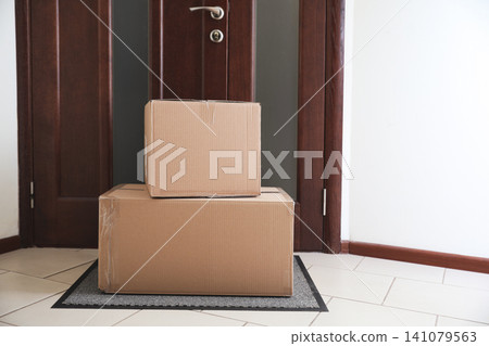 Cardboard boxes on rug near door. Parcel delivery service Cardboard boxes on rug near door. Parcel delivery service 141079563