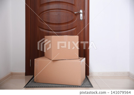 Cardboard boxes on rug near door. Parcel delivery service Cardboard boxes on rug near door. Parcel delivery service 141079564