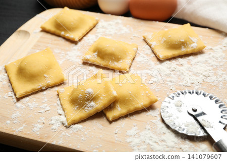 Raw ravioli on wooden board, closeup view. Italian pasta Raw ravioli on wooden board, closeup view. Italian pasta 141079607