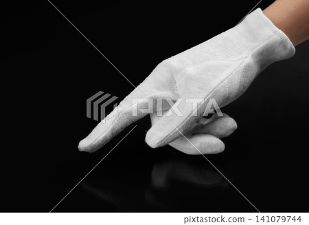 Person in white glove checking cleanliness of black background, closeup Person in white glove checking cleanliness of black background, closeup 141079744