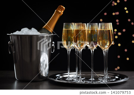 Glasses of champagne and ice bucket with bottle on grey table Glasses of champagne and ice bucket with bottle on grey table 141079753