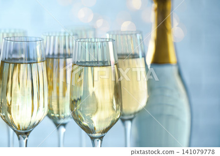 Glasses and bottle of champagne against blurred lights, closeup Glasses and bottle of champagne against blurred lights, closeup 141079778