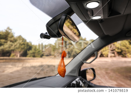 Air freshener hanging on rear view mirror in car Air freshener hanging on rear view mirror in car 141079819