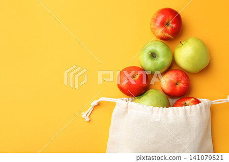 Cotton eco bag and apples on yellow background, flat lay. Space for text Cotton eco bag and apples on yellow background, flat lay. Space for text 141079821
