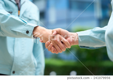 The hands of a man in work clothes shaking hands The hands of a man in work clothes shaking hands 141079956