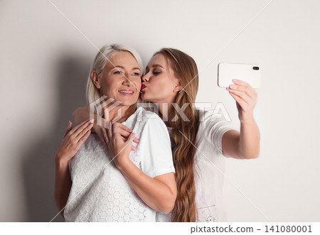 Happy mother and daughter taking selfie on white background Happy mother and daughter taking selfie on white background 141080001