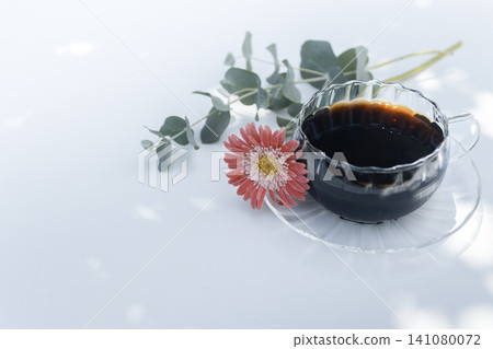 Iced coffee and gerberas against a white background with sunlight filtering through the trees. (Copy space) Iced coffee and gerberas against a white background with sunlight filtering through the trees. (Copy space) 141080072