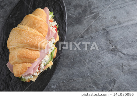 Tasty croissant sandwich with ham on grey table, top view. Space for text 141080096