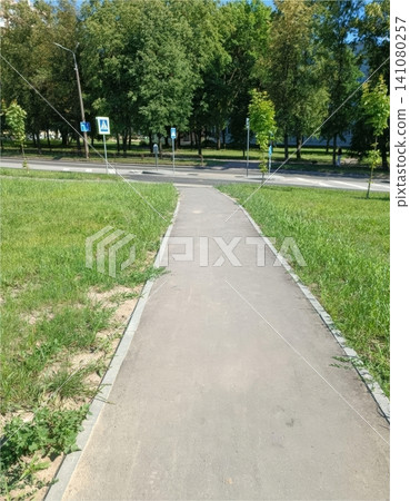 Paved pathway through green park with trees and road signs under sunny sky Paved pathway through green park with trees and road signs under sunny sky 141080257