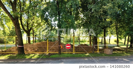 Yellow construction fence with no entry sign in park under green trees Yellow construction fence with no entry sign in park under green trees 141080260