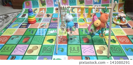 Baby play gym on colorful educational alphabet mat with hanging toys 141080291