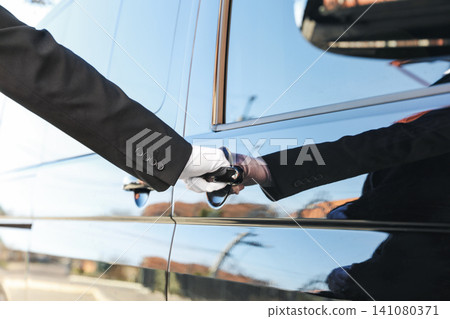 Driver opening door of luxury car, closeup. Chauffeur service Driver opening door of luxury car, closeup. Chauffeur service 141080371